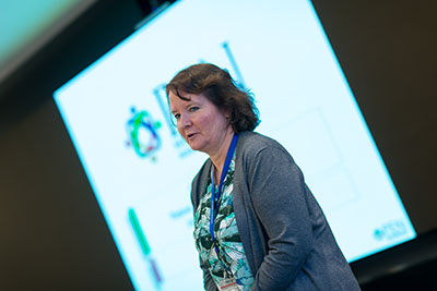 Woman standing in front of a screen giving a presentation